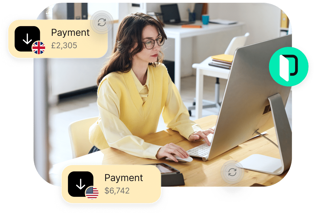 A person working at a desk on a computer with notifications of payments received: £2,305 from the UK and $6,742 from the US.