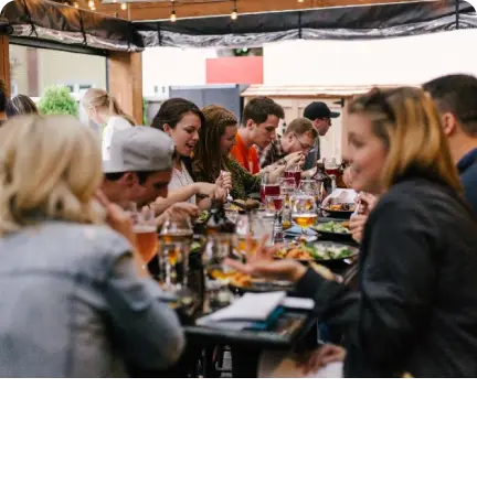 A group of people enjoying a career update over a meal at an outdoor table.