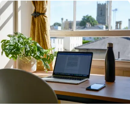 A laptop sits on a desk in front of a window, providing the perfect setup for a career update.