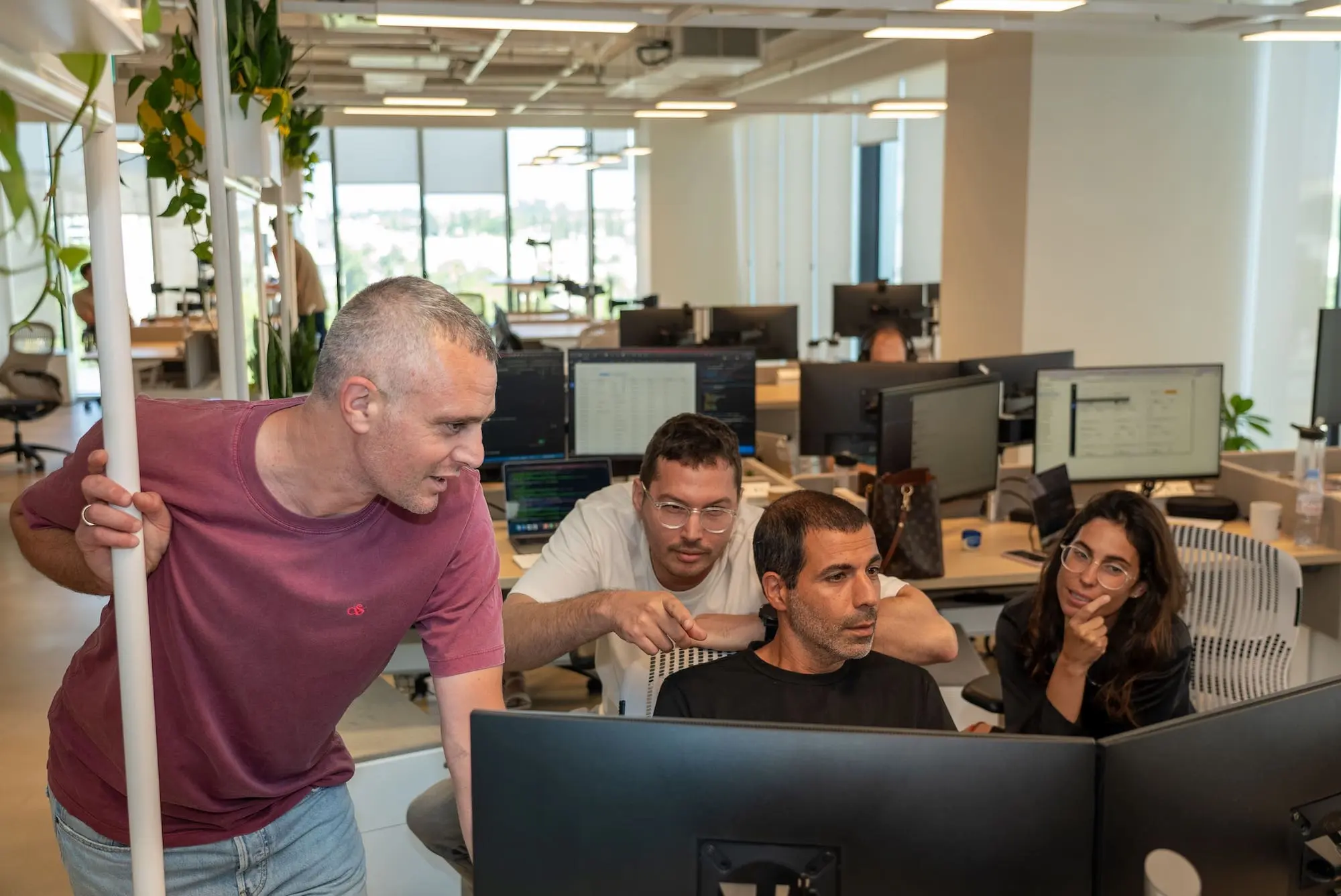 A group of people in an office looking at computers.